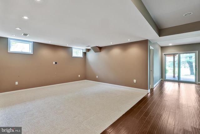 below grade area with baseboards, dark wood-type flooring, visible vents, and recessed lighting