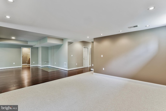 below grade area with recessed lighting, visible vents, baseboards, and dark wood-style floors