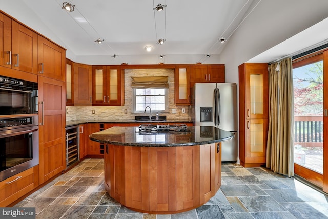 kitchen with a sink, stone tile floors, gas stovetop, stainless steel fridge, and wine cooler