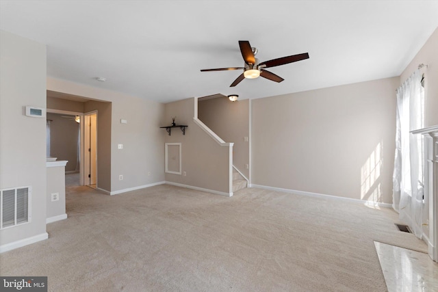 unfurnished living room with visible vents, a ceiling fan, stairway, and light colored carpet