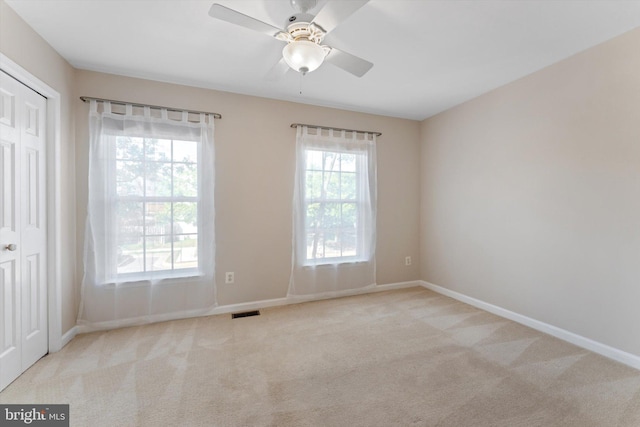 carpeted spare room with ceiling fan, visible vents, and baseboards
