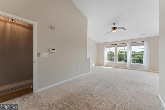 carpeted spare room with baseboards, a ceiling fan, vaulted ceiling, and visible vents