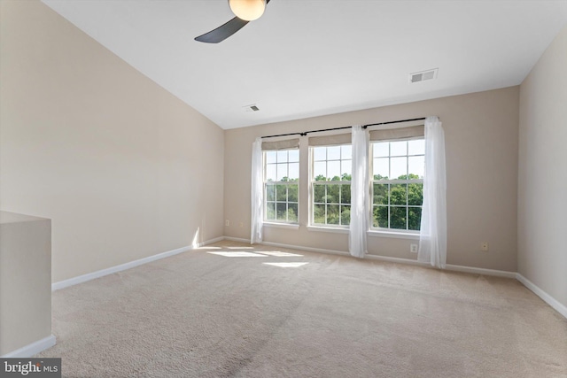 carpeted spare room featuring baseboards, a ceiling fan, lofted ceiling, and visible vents