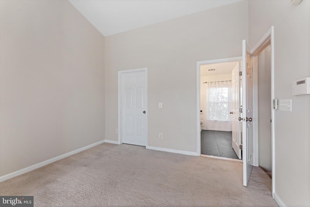 unfurnished bedroom featuring carpet floors, baseboards, and ensuite bath