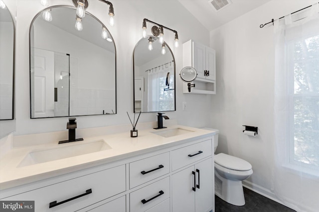full bathroom with visible vents, a sink, double vanity, and toilet