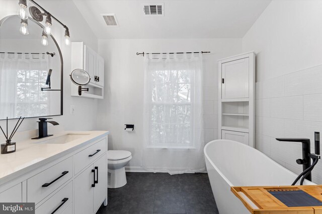 bathroom featuring visible vents, plenty of natural light, tile patterned floors, and a soaking tub