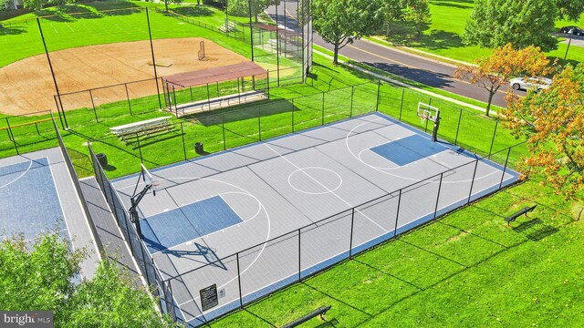 view of basketball court with a lawn, community basketball court, and fence