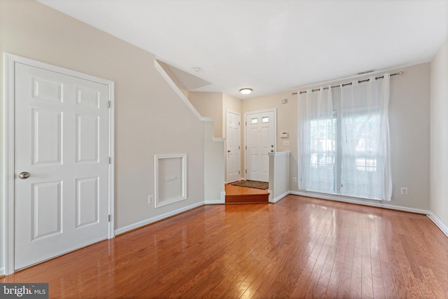 foyer featuring baseboards, wood finished floors, and stairway