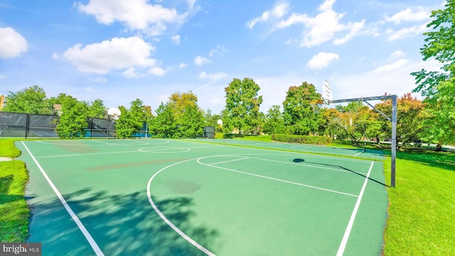 view of basketball court featuring a lawn, community basketball court, and fence