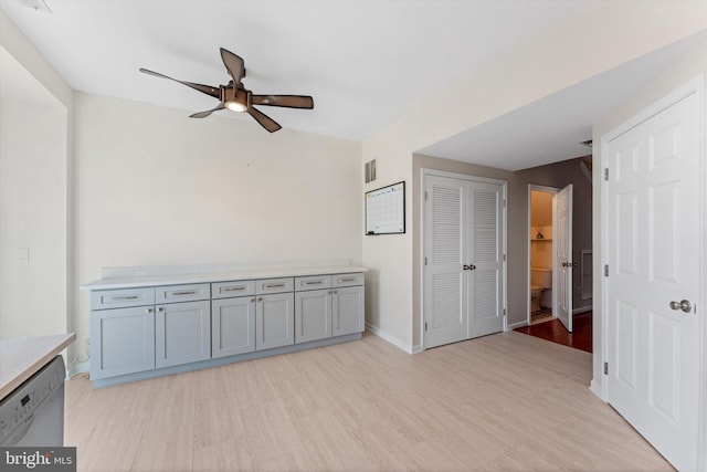 empty room with baseboards, a ceiling fan, light wood finished floors, and visible vents