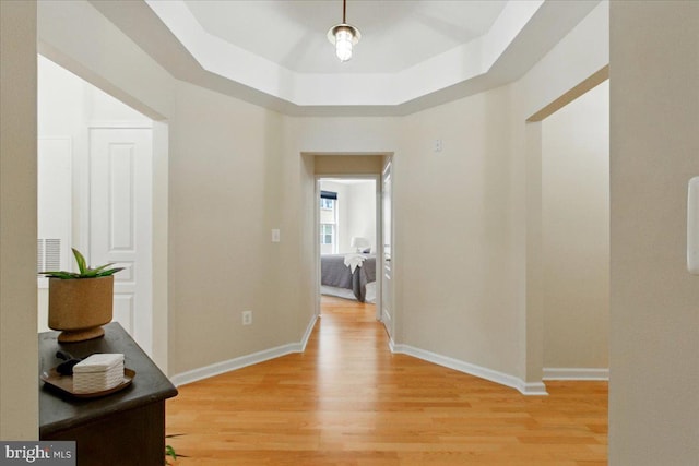 12000 Market St Unit 189, Reston, VA 20190 - hallway featuring a tray ceiling, baseboards, and light wood-style floors