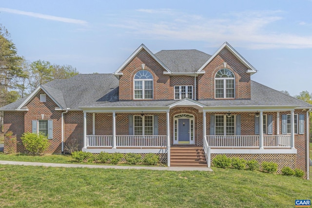 view of front of property with brick siding, a shingled roof, a front lawn, and covered porch