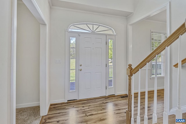 entryway with ornamental molding, wood finished floors, stairway, and a healthy amount of sunlight