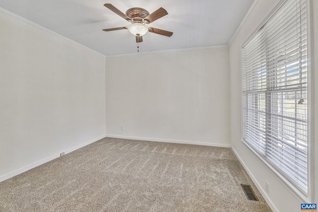 carpeted spare room featuring crown molding, a ceiling fan, visible vents, and a healthy amount of sunlight