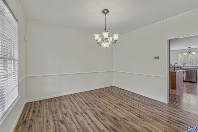 spare room featuring baseboards, crown molding, a chandelier, and dark wood-type flooring