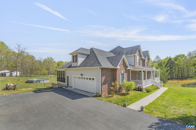 view of property exterior with driveway, covered porch, brick siding, a garage, and a yard