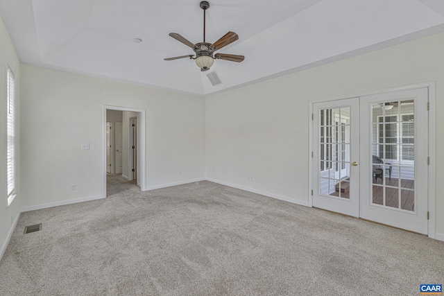carpeted empty room with french doors, a tray ceiling, baseboards, visible vents, and a ceiling fan