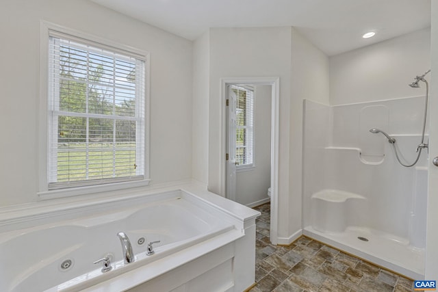 bathroom featuring plenty of natural light, a shower, and a tub with jets