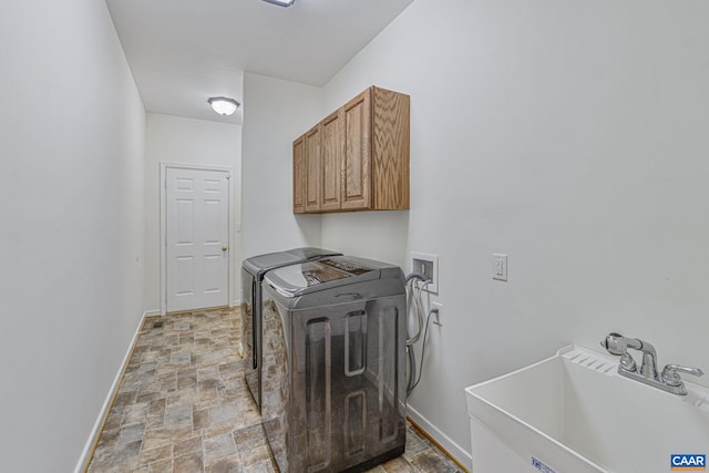 laundry area with a sink, stone finish flooring, baseboards, separate washer and dryer, and cabinet space