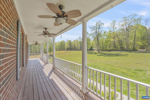 deck featuring a ceiling fan, a lawn, and covered porch