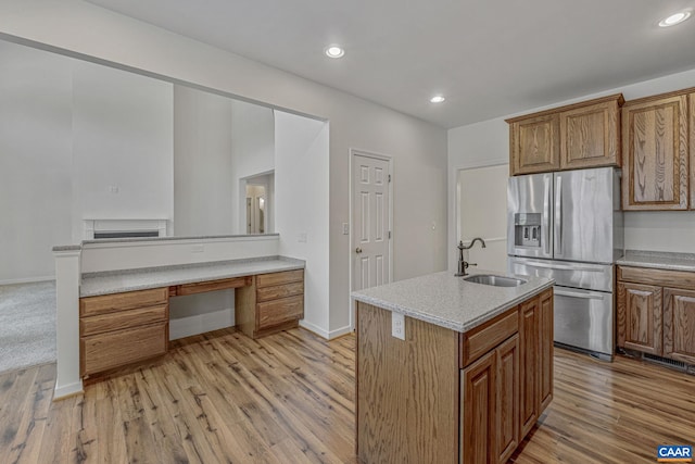 kitchen featuring stainless steel refrigerator with ice dispenser, light wood-style flooring, a sink, and brown cabinets