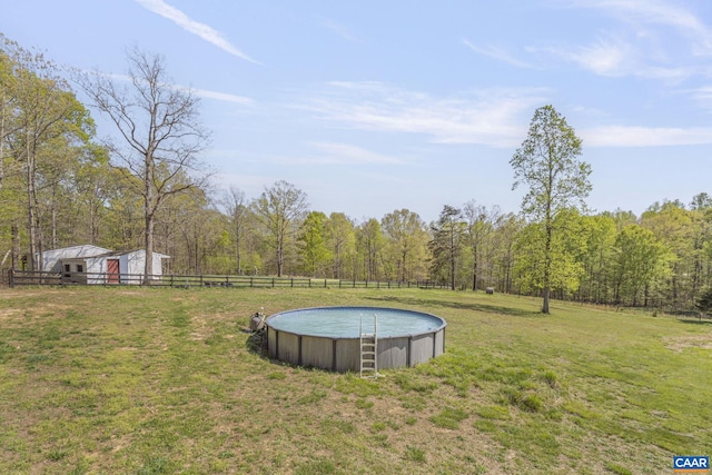 view of yard with fence, an outdoor pool, and a forest view