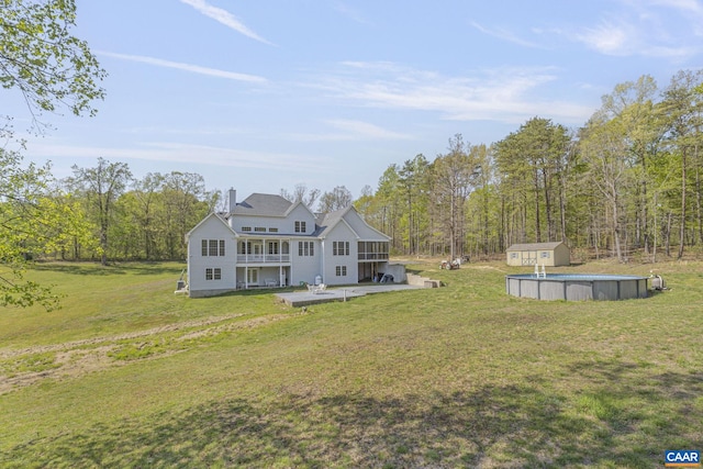 rear view of property featuring a storage unit, an outbuilding, a patio, and a lawn