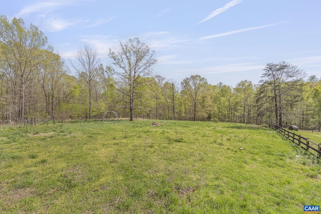 view of yard featuring a wooded view and fence