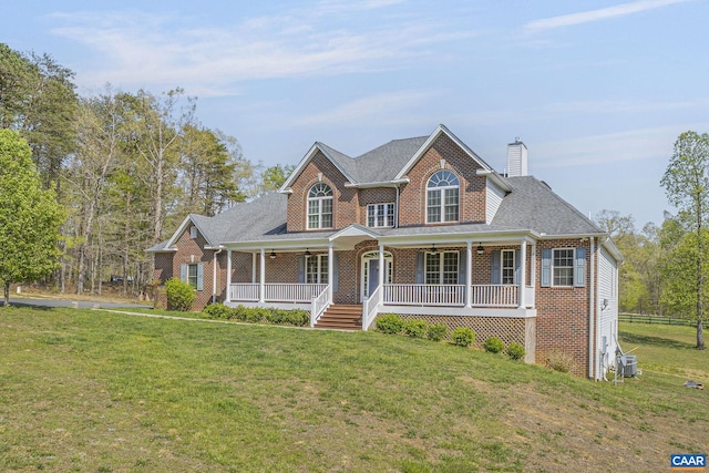 view of front of house with ceiling fan, a front lawn, covered porch, and brick siding