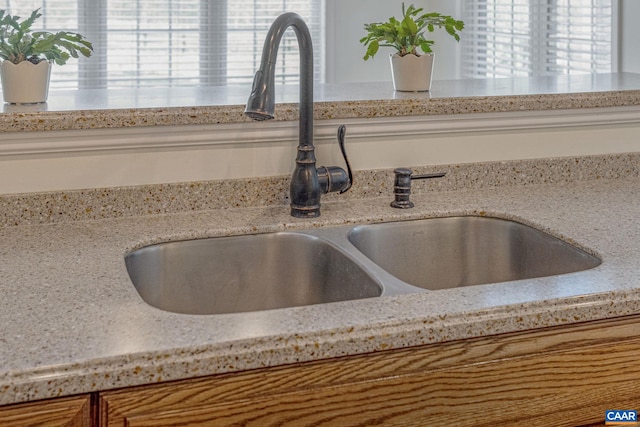 room details with light stone countertops and a sink