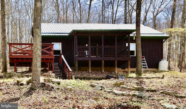 rear view of house featuring stairs, metal roof, and a deck