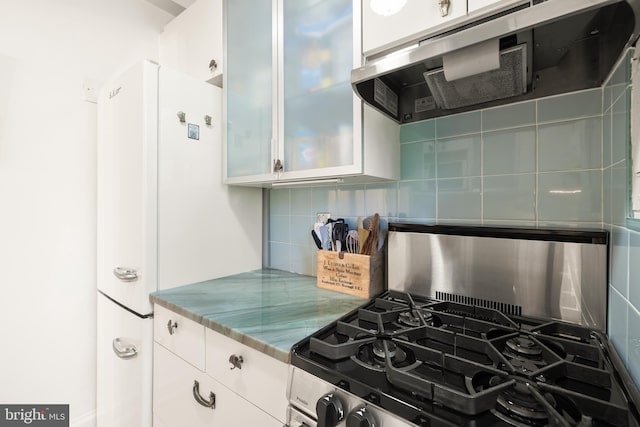 kitchen featuring decorative backsplash, gas range, light stone counters, white cabinets, and extractor fan