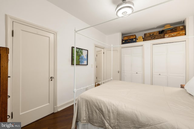 bedroom featuring multiple closets, baseboards, and dark wood-style flooring
