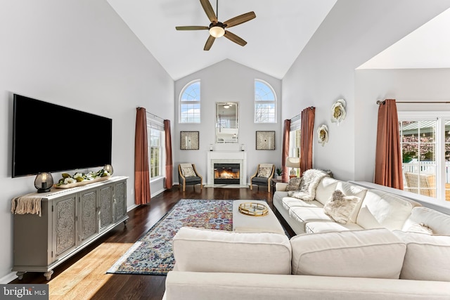 living room featuring a fireplace with flush hearth, high vaulted ceiling, dark wood-type flooring, and ceiling fan