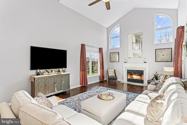 living room with a ceiling fan, wood finished floors, high vaulted ceiling, and a high end fireplace