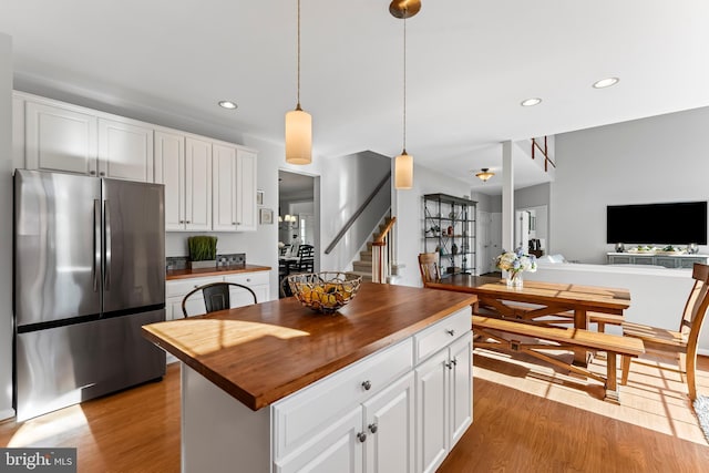 kitchen with wood counters, white cabinetry, light wood-type flooring, and freestanding refrigerator