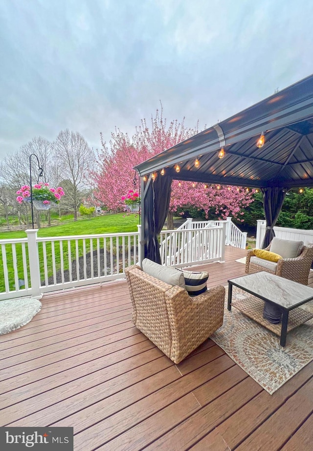 wooden terrace featuring a lawn, outdoor lounge area, and a gazebo