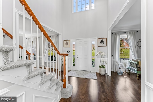 foyer entrance featuring a high ceiling, stairs, and dark wood-style flooring