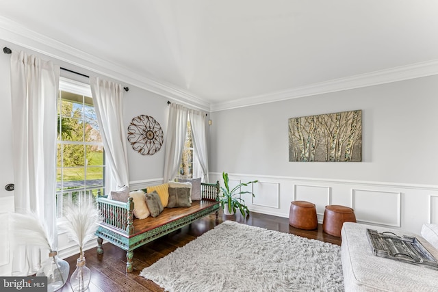 living area featuring ornamental molding, a wainscoted wall, and wood finished floors
