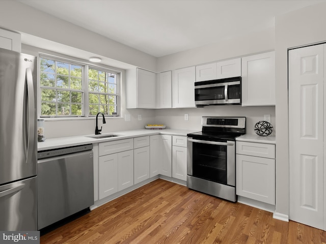2607 Nisqually Ct, Silver Spring, MD 20906 - kitchen featuring stainless steel appliances, light wood-style floors, light countertops, white cabinets, and a sink