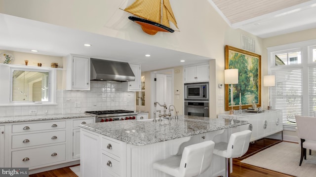 213 S Morris St, Oxford, MD 21654 - kitchen featuring white cabinets, dark wood finished floors, wall chimney range hood, and stainless steel appliances
