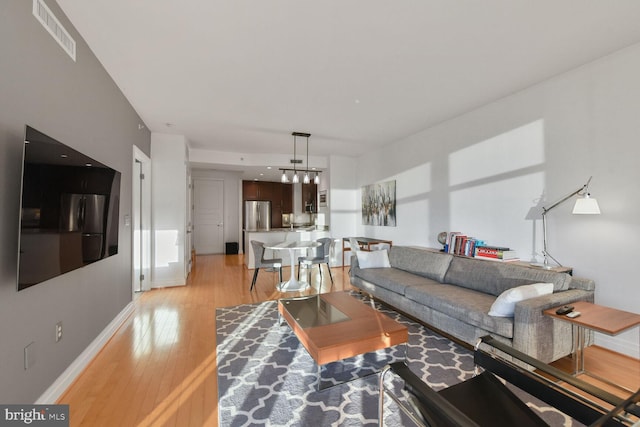 living room featuring baseboards, visible vents, and light wood-type flooring