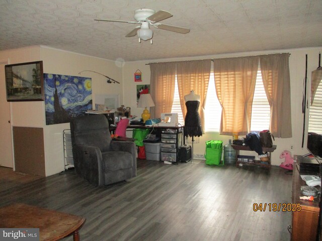 living area with crown molding, a ceiling fan, and wood finished floors
