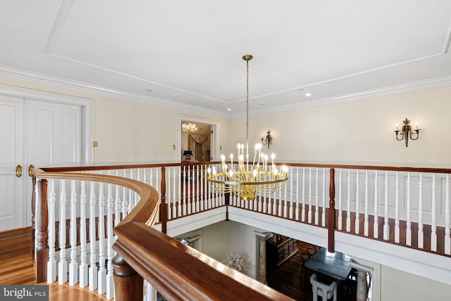 hallway with an upstairs landing, ornamental molding, a chandelier, and wood finished floors