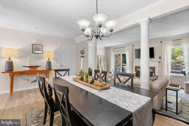 dining area with healthy amount of natural light, light wood-style floors, a textured ceiling, a chandelier, and crown molding