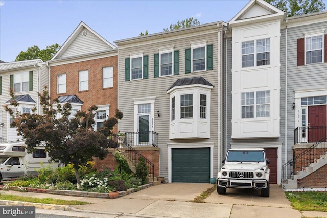 townhome / multi-family property with concrete driveway, an attached garage, and stairs
