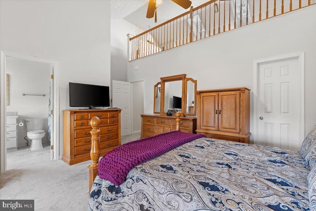 carpeted bedroom with a towering ceiling, ensuite bath, and baseboards