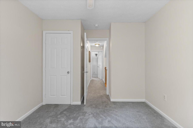 unfurnished bedroom featuring carpet, baseboards, and a textured ceiling