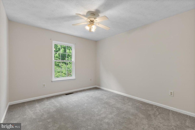spare room with baseboards, carpet, a ceiling fan, and a textured ceiling