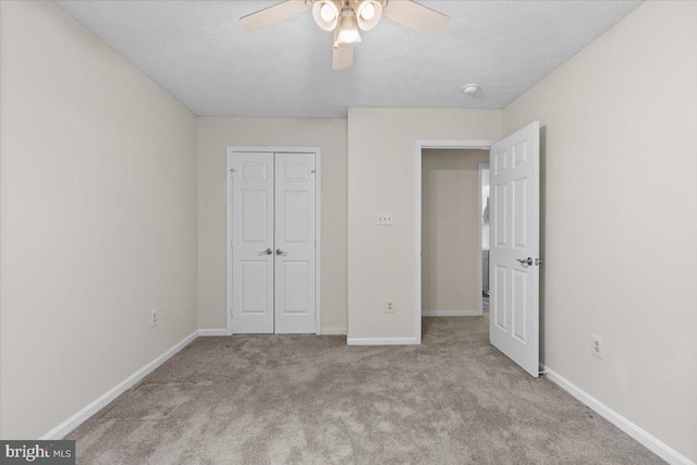 unfurnished bedroom featuring carpet flooring, a closet, baseboards, a textured ceiling, and ceiling fan